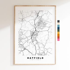 May include: A framed monochrome map print of Hatfield, showing the road network. The town's name and coordinates are at the bottom. The print is in a light wood frame, suitable for home decor.