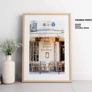 May include: A framed photograph of a Parisian cafe with a white awning and string lights. The cafe sign reads "Cafe" and "Vins de Propriete Cocktails Cuisine Soignee".