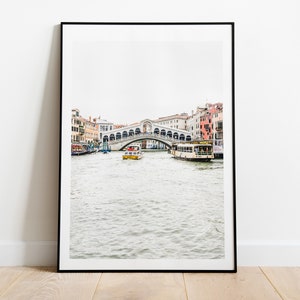 Puede incluir: Una fotograf&iacute;a en blanco y negro de un puente en Venecia, Italia. El puente es arqueado y tiene una estructura de piedra blanca. Hay barcos en el agua debajo del puente.