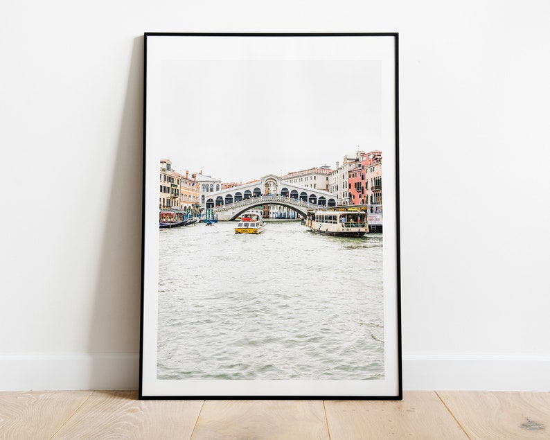 Puede incluir: Una fotograf&iacute;a en blanco y negro de un puente en Venecia, Italia. El puente es arqueado y tiene una estructura de piedra blanca. Hay barcos en el agua debajo del puente.