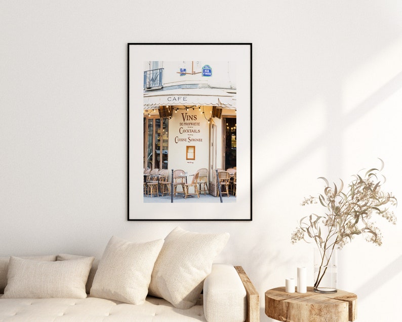 May include: A black and white photo of a Parisian cafe with a sign that reads "Vins en Propriete, Cocktails, Cuisine Savoureuse" and a cafe sign that reads "Cafe".