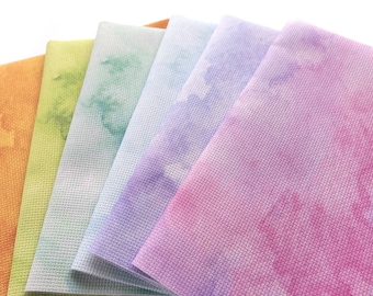 May include: A stack of six fabric squares in various pastel colors, including orange, yellow, green, blue, purple, and pink. The fabric has a subtle texture and a tie-dye pattern.
