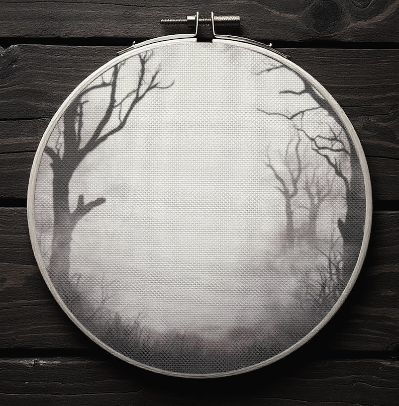 Pode incluir: Um bastidor de bordado a preto e branco com uma cena de floresta enevoada com &aacute;rvores despidas. A obra de arte &eacute; definida contra um fundo cinzento, criando um efeito atmosf&eacute;rico. O bastidor &eacute; de metal e est&aacute; montado numa superf&iacute;cie de madeira escura.