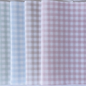 May include: A collection of folded fabric napkins in various pastel colors, including green, blue, and pink. Each napkin features a classic gingham check pattern in white and a coordinating color. The napkins are neatly stacked.