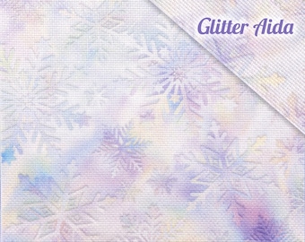 May include: A close-up of white fabric with a subtle, textured pattern. The fabric has a faint, watercolor-like design of purple, blue, and yellow flowers. The text "Glitter Aida" is printed in purple at the top right corner of the image.