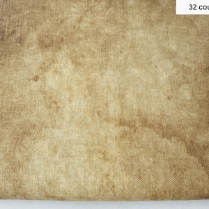 Puede incluir: Un primer plano de un trozo de tela de lino de 32 hilos. La tela es de color marrón claro con una textura sutil.