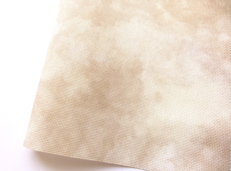 May include: Close-up of a beige fabric with a subtle woven texture. The fabric has a slightly off-white hue and a smooth, even surface.