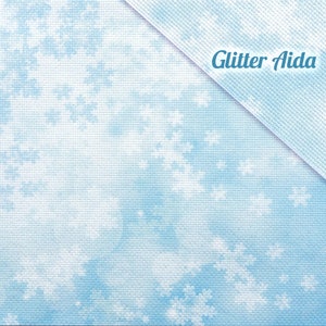 Pode incluir: Tecido Aida azul claro com um padrão sutil de nuvens brancas. O tecido é etiquetado como "Glitter Aida".