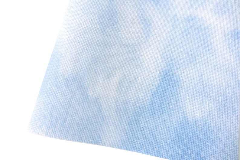 May include: A light blue fabric with a white and light blue tie-dye pattern. The fabric has a woven texture.