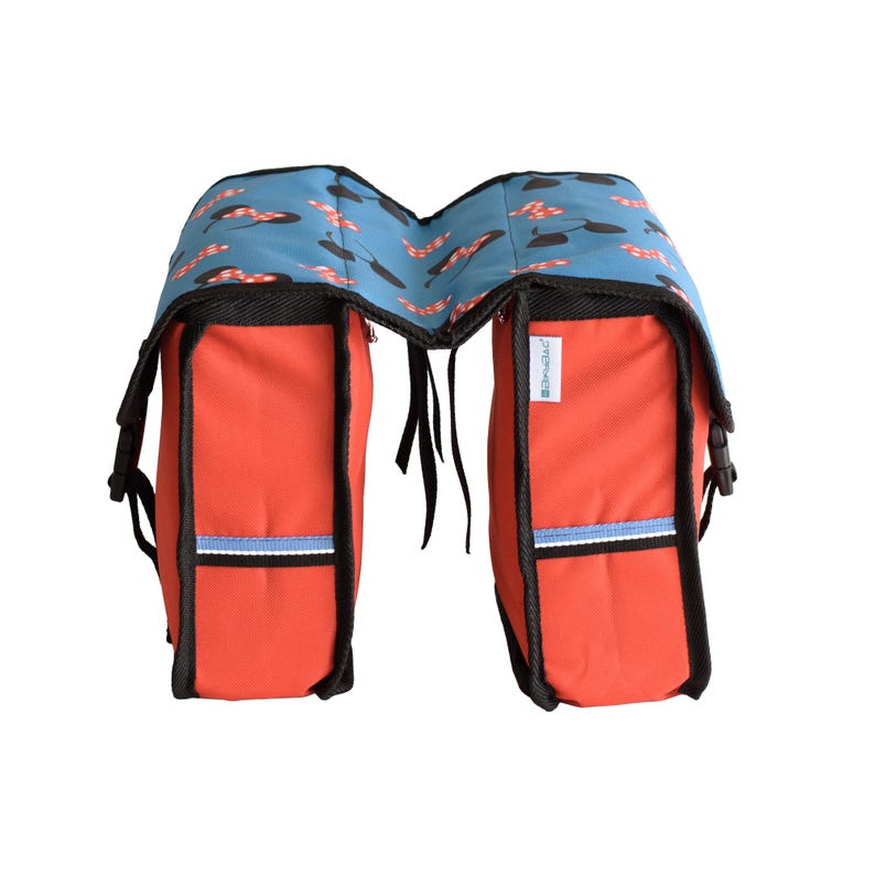 May include: A double bicycle pannier bag featuring a bright red main body with black trim and a blue top flap decorated with a repeating pattern of black mouse ears and red polka-dot bows. The bag includes side buckles and a small white label.