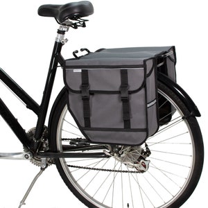 Peut inclure: Un sac de v&eacute;lo gris avec des sangles et des boucles noires, fix&eacute; au porte-bagages arri&egrave;re d'un v&eacute;lo noir.