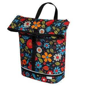 Könnte beinhalten: Schwarzer Rucksack mit Blumenmuster, Rollverschluss und schwarzem Griff. Das farbenfrohe Design zeigt orange, rote, blaue und weiße Blumen mit grünen Blättern. Die Tasche hat einen weißen Streifen am Boden.