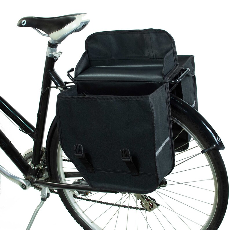 Peut inclure: Deux sacoches de v&eacute;lo noires avec un rabat sup&eacute;rieur et des boucles. Les sacoches sont fix&eacute;es &agrave; un v&eacute;lo noir avec une selle noire.