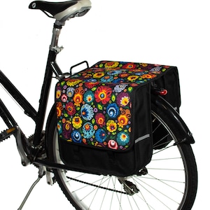 Pu&ograve; includere: Bicicletta nera con una borsa da portapacchi a fantasia floreale fissata al portapacchi posteriore. La borsa da portapacchi ha una base nera e un motivo floreale colorato con fiori rossi, gialli, blu, verdi e bianchi.