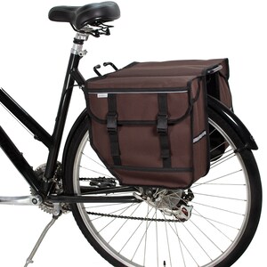 Peut inclure: Un sac de v&eacute;lo brun &agrave; deux compartiments et des sangles r&eacute;glables, fix&eacute; &agrave; un v&eacute;lo noir.