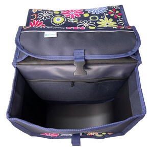 Puede incluir: Una bolsa de compras plegable azul con estampado floral y un bolsillo con cremallera. La bolsa est&aacute; abierta y el interior es visible. La bolsa tiene una correa y una hebilla.