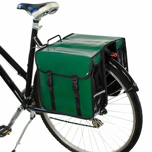 May include: A green and black bicycle pannier bag with a reflective strip. The bag is attached to the rear rack of a bicycle.