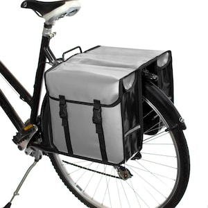 May include: A pair of gray and black bicycle panniers with reflective accents attached to a black bicycle.