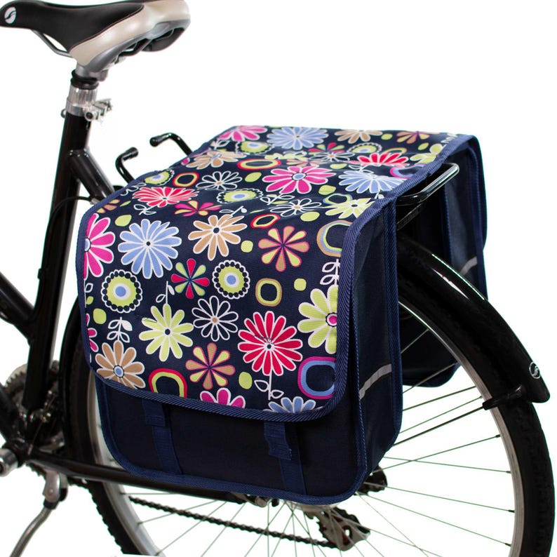 Pu&ograve; includere: Un paio di borse da bicicletta blu con stampa floreale. Le borse sono attaccate a una bicicletta nera.
