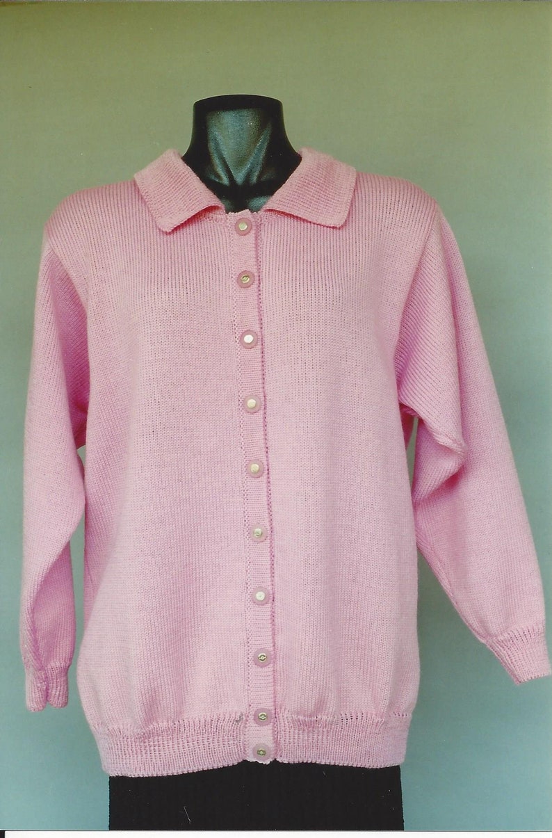 May include: A pink knitted cardigan with a collared neckline and a button-up front. The cardigan has long sleeves and a ribbed texture.