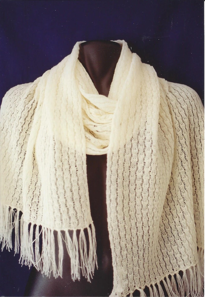May include: A white crocheted scarf with a fringe on the ends. The scarf is draped over a mannequin.