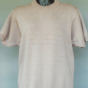 May include: A light beige knitted short-sleeved sweater with a round neckline.
