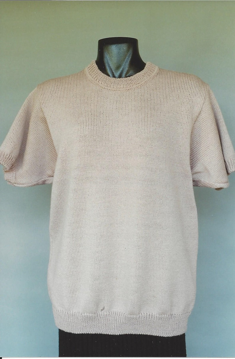May include: A light beige knitted short-sleeved sweater with a round neckline.