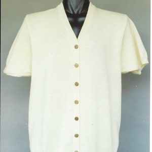 May include: A white short-sleeved cardigan with a v-neck and button closure. The cardigan has a ribbed texture and is made of a soft, lightweight material.