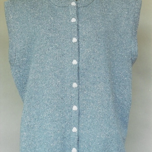 May include: A light blue sleeveless cardigan with a button-up front. The cardigan is made of a soft, textured fabric.