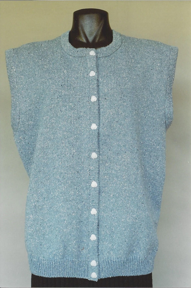 May include: A light blue sleeveless cardigan with a button-up front. The cardigan is made of a soft, textured fabric.