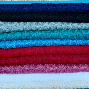 May include: A stack of ten knitted fabric swatches in various colors, including navy blue, black, silver, teal, light blue, red, burgundy, white, and beige.