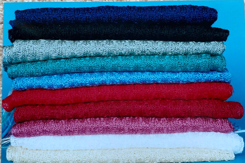 May include: A stack of ten knitted fabric swatches in various colors, including navy blue, black, silver, teal, light blue, red, burgundy, white, and beige.