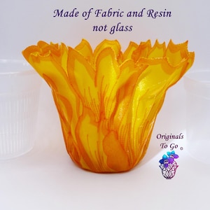 May include: A yellow fabric flower pot made of fabric and resin. The pot is sitting on a white surface. The text "Made of Fabric and Resin not glass" is written above the pot. The text "Originals To Go" is written below the pot.
