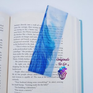 May include: A blue and white acrylic bookmark with a wave design. The bookmark has the text "Six-Originals To Go" printed on it.