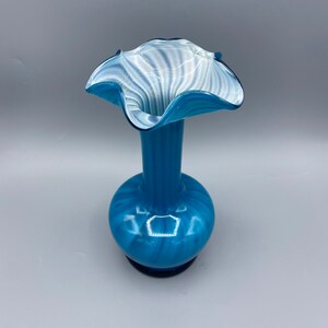 Puede incluir: Un jarr&oacute;n de vidrio azul y blanco con la parte superior con volantes. El jarr&oacute;n tiene un patr&oacute;n de espiral y un acabado brillante.