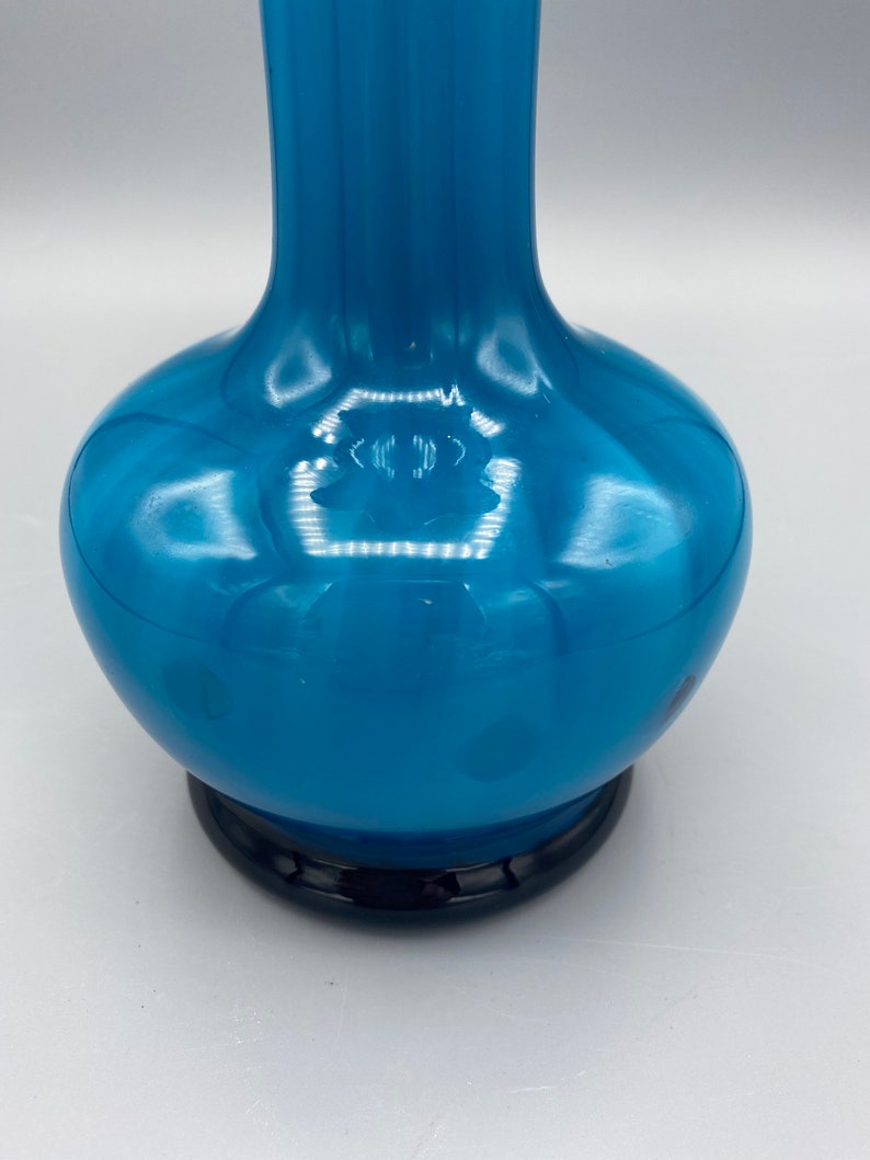 Puede incluir: Un jarr&oacute;n de vidrio azul alto y redondo, con una base azul oscuro. El jarr&oacute;n tiene un acabado brillante y un patr&oacute;n sutil.