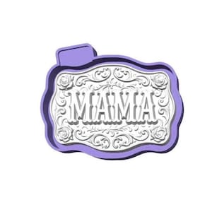 May include: A decorative, lavender-edged plaque with the word "MAMA" in the center. The white interior features ornate floral and scrollwork designs. The plaque has a rectangular shape with a curved bottom and a small tab at the top.