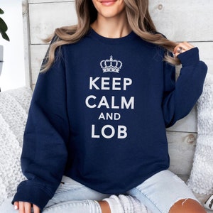 May include: Navy blue sweatshirt with a white crown and the text "Keep Calm and LOB" printed on the front.