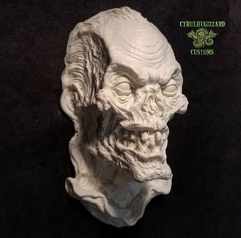 K&ouml;nnte beinhalten: Eine wei&szlig;e Gips-Skulptur eines Zombiekopfes mit einem detaillierten, grotesken Ausdruck. Die Skulptur ist auf einem Sockel montiert und hat eine strukturierte Oberfl&auml;che.