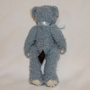 May include: A light blue plush teddy bear with a brown tail and a light blue ribbon around its neck.