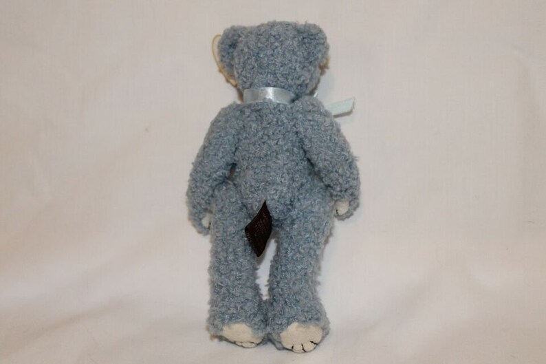 May include: A light blue plush teddy bear with a brown tail and a light blue ribbon around its neck.