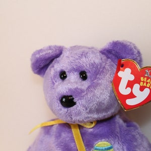 May include: Purple Ty Beanie Baby with a yellow ribbon and an Easter egg design. The tag reads "10th Anniversary Beanie Babies".
