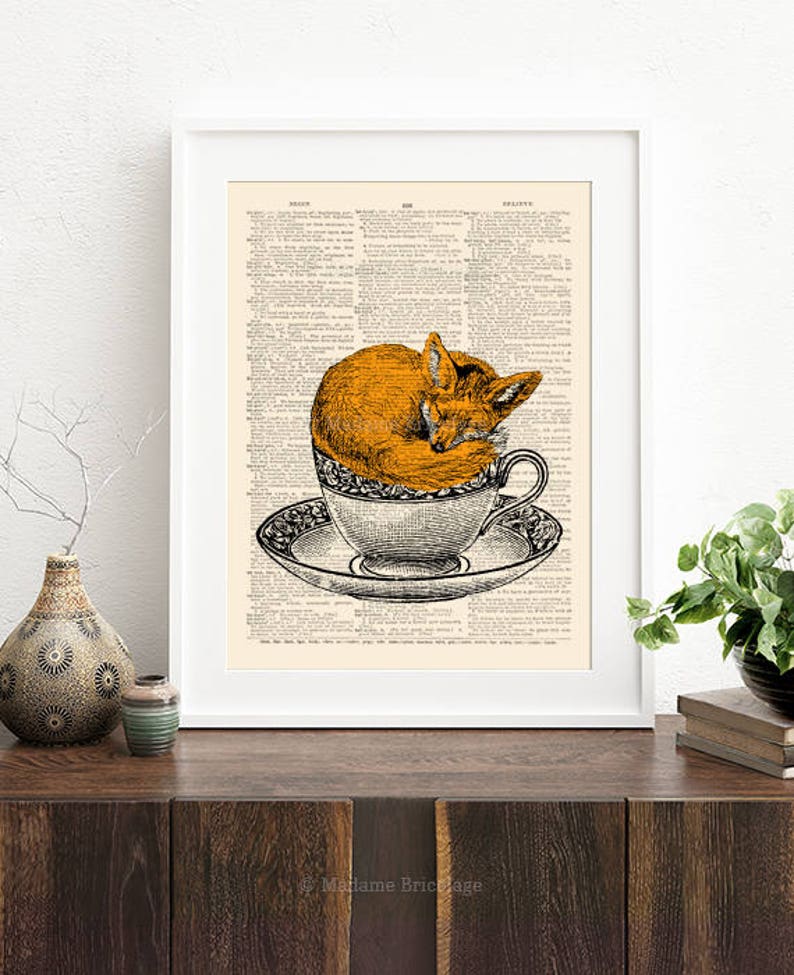K&ouml;nnte beinhalten: Eine Vintage-W&ouml;rterbuchseite mit einer Illustration eines Fuchses, der in einer Teetasse eingeschlafen ist. Der Fuchs ist orange und die Teetasse ist wei&szlig; mit einem schwarz-wei&szlig;en Blumenmuster.
