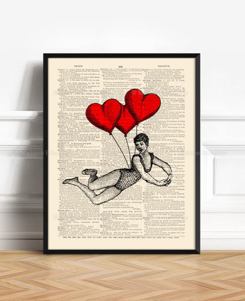 May include: A black and white illustration of a woman flying with three red heart-shaped balloons. The woman is wearing a swimsuit and is holding onto the balloons with her hands. The illustration is printed on a vintage dictionary page.