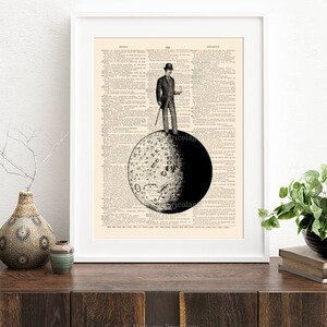 May include: A black and white illustration of a man in a top hat standing on the moon. The moon is depicted with craters and a dark side. The illustration is printed on a vintage dictionary page.