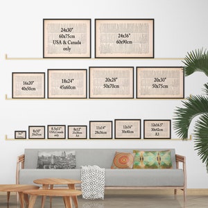 K&ouml;nnte beinhalten: Eine wei&szlig;e Wand mit einem Regal, auf dem verschiedene Gr&ouml;&szlig;en von gerahmten Schwarzwei&szlig;drucken ausgestellt sind. Die Drucke haben alle das gleiche Design, einen Vintage-Zeitungsartikel. Die Gr&ouml;&szlig;en sind in Zoll und Zentimetern angegeben. Das Regal ist aus Holz und an der Wand montiert. Vor dem Regal steht eine graue Couch mit Kissen.