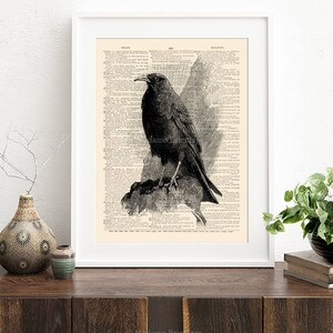 May include: A black and white illustration of a crow perched on a branch, printed on a vintage book page. The image is framed in a white frame.
