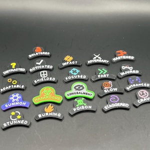May include: A collection of black, curved tokens with various colorful icons and text. The tokens feature words like "Distracted," "Activated," "Impact," and "Fast." The tokens are likely used in a tabletop game or similar activity.