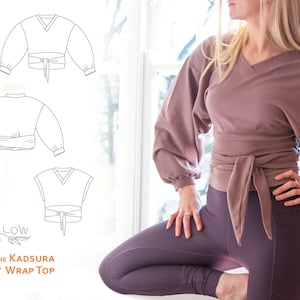 Puede incluir: Un top de color malva con mangas largas y cuello en V. El top está atado a la cintura con una cinta. El texto "The Kadsura Waist Wrap Top" es visible debajo de la imagen.