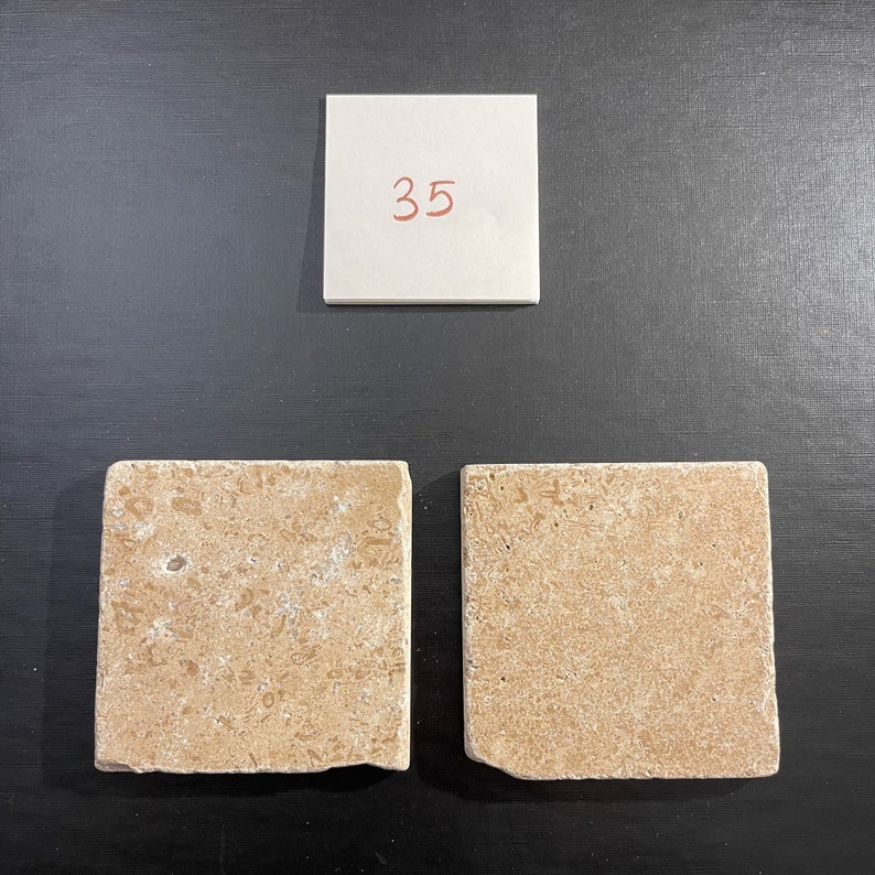 May include: Two beige square tiles with a rough texture. The tiles are numbered 35 on a white note.